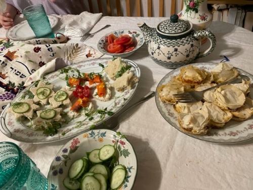 tea table spread with deviled eggs, finger sandwiches, mini vegetable pies, and dessert plate of mini pastries, cookies and fruit