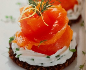 smoked salmon rolled and garnished with dill and lemon zest on a pumpernickle toast round